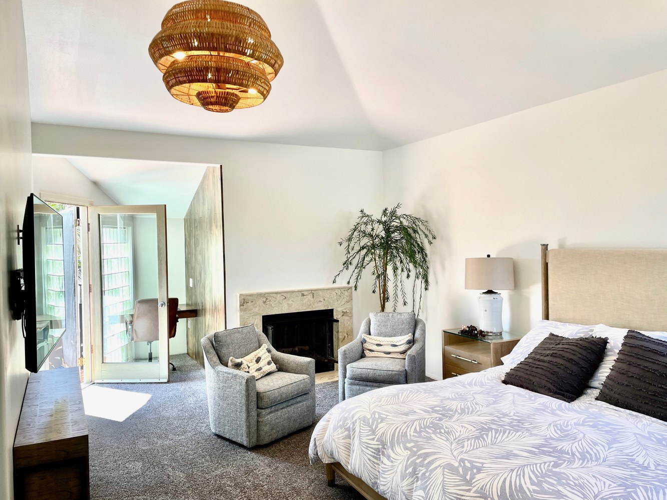 Primary bedroom — fireplace, rattan chandelier