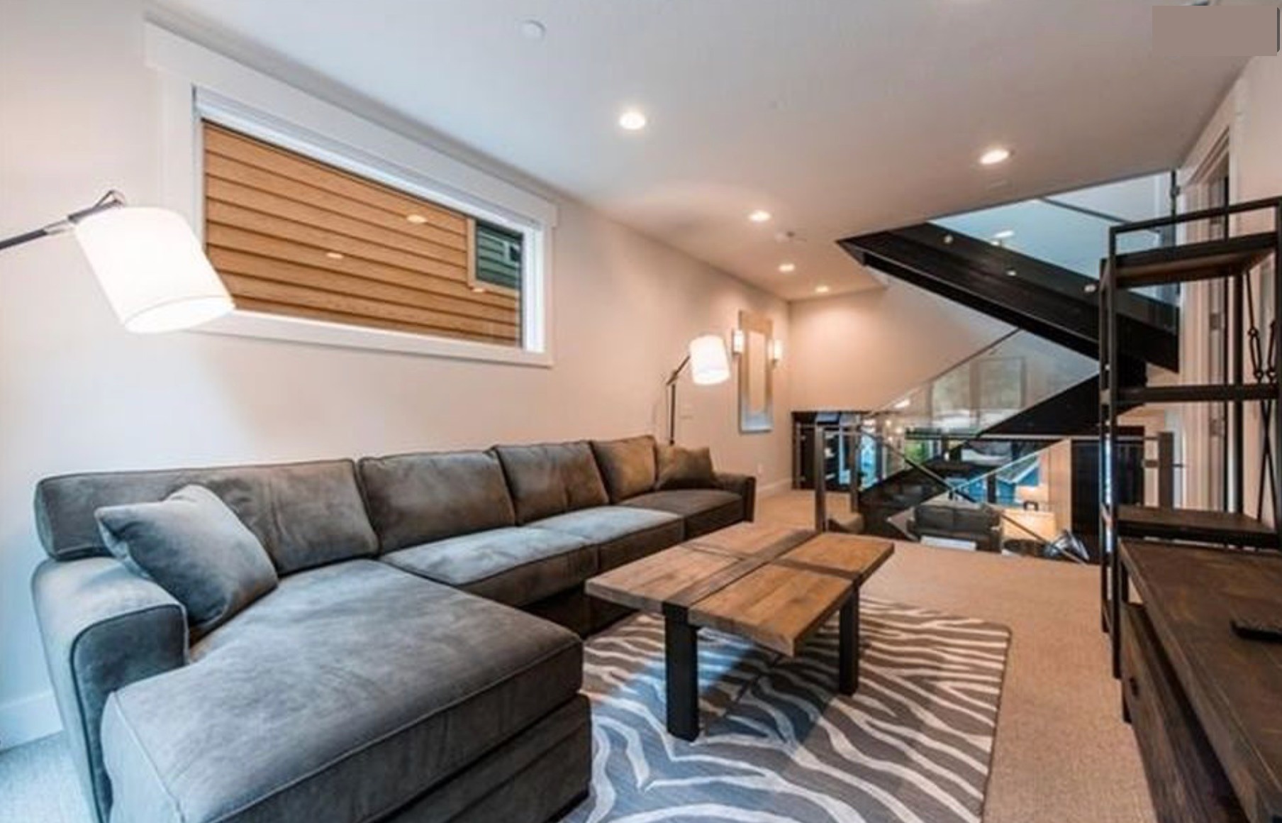 Family room with sectional and zebra rug, staircase to upper level