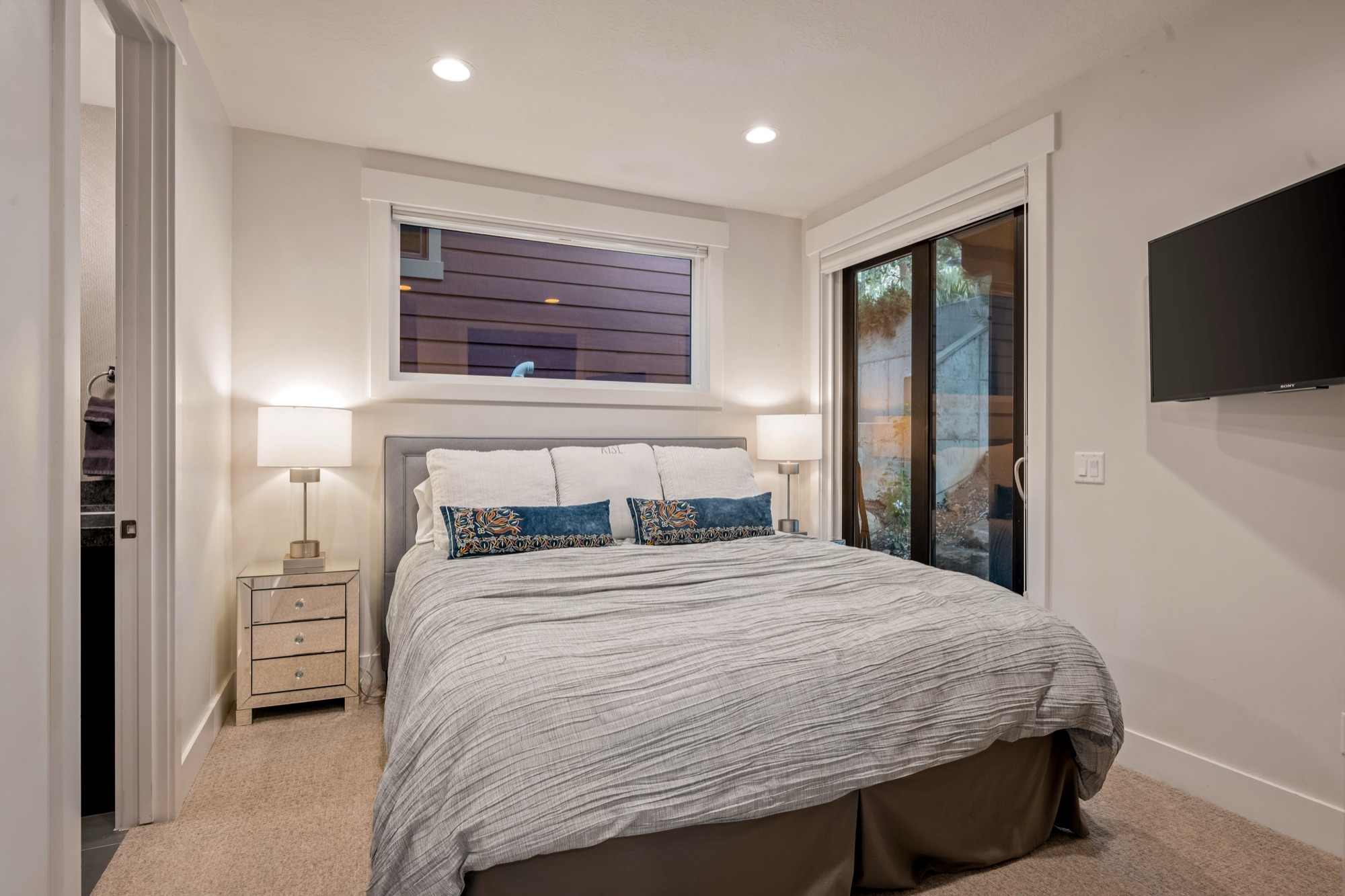 Third bedroom — king bed, dark beam, sliding door to deck